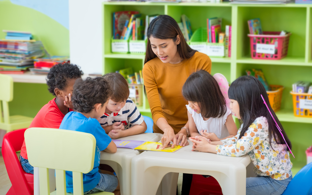 Young Asian teacher sitting around a table with small group of students